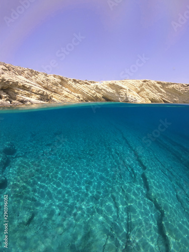 Above and below underwater photo of crystal clear sea paradise rocky seascape of Laki beach in Kato Koufonisi island, Cyclades, Greece © aerial-drone