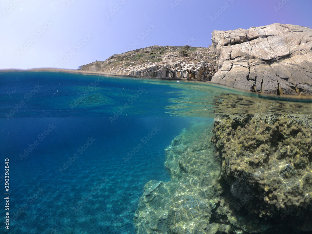 Above and below underwater photo of crystal clear sea paradise rocky seascape and small chapel of Agia Anna just next to iconic Hozoviotissa Monastery, Amorgos island, Cyclades, Greece