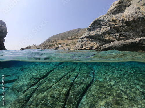 Above and below underwater photo of crystal clear sea paradise rocky seascape and small chapel of Agia Anna just next to iconic Hozoviotissa Monastery, Amorgos island, Cyclades, Greece photo