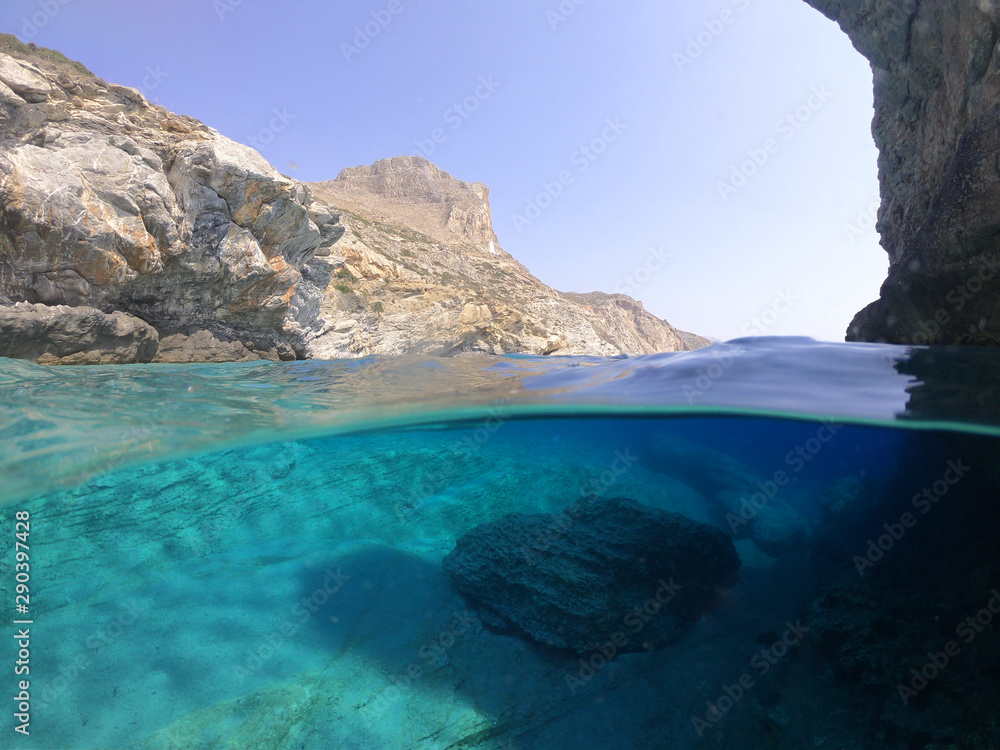 Above and below underwater photo of crystal clear sea paradise rocky seascape full of caves beach of Mouros, Amorgos island, Cyclades, Greece