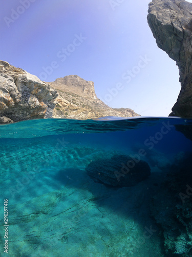 Above and below underwater photo of crystal clear sea paradise rocky seascape full of caves beach of Mouros  Amorgos island  Cyclades  Greece