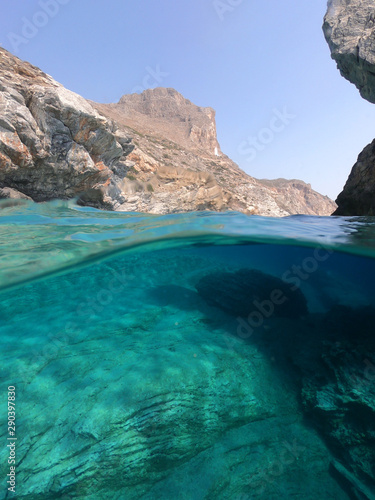 Above and below underwater photo of crystal clear sea paradise rocky seascape and small chapel of Agia Anna just next to iconic Hozoviotissa Monastery  Amorgos island  Cyclades  Greece