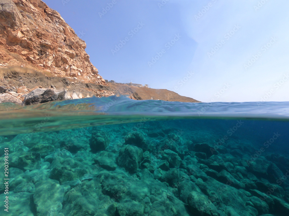 Beautiful underwater split above and below photo of rocky seascape with deep blue sky and clouds in tropical exotic island destination
