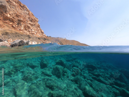 Beautiful underwater split above and below photo of rocky seascape with deep blue sky and clouds in tropical exotic island destination