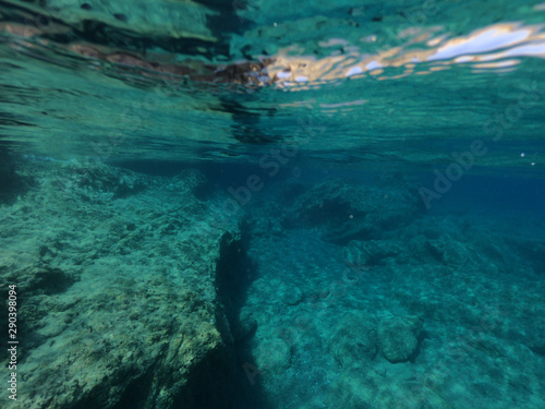 Beautiful underwater split above and below photo of rocky seascape with deep blue sky and clouds in tropical exotic island destination