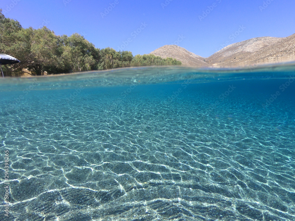 Above and below underwater photo of crystal clear turquoise beach of Kaminakia, Astypalaia island, Dodecanese, Greece