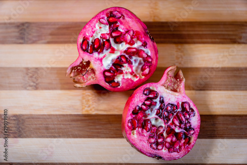 pomegranate fruit sliced on a wooden cutting board. Ripe pomegranate closeup with selective focus