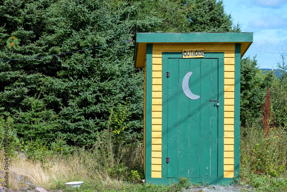 Yellow outhouse with green trim and green door. There's a white half