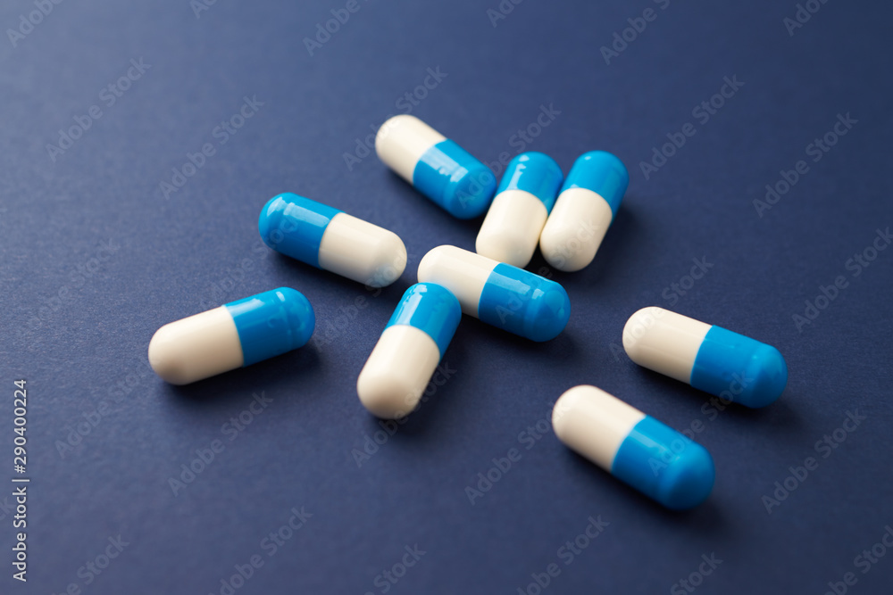Tri-Creatine Malate capsules. Bodybuilding food supplements on blue paper background. Close up. Copy space. 