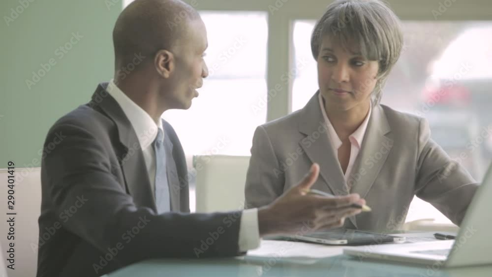 Businessman and businesswoman talking at table with laptop Businessman and businesswoman talking at table with laptop