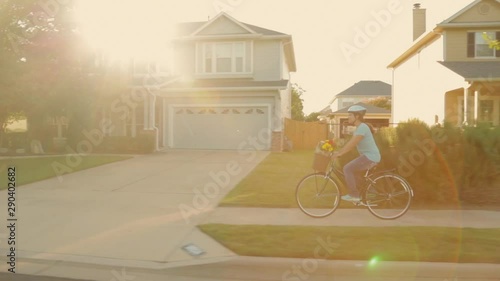Hispanic woman riding bicycle with groceries through neighborhood