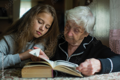 Cute little girl with her grandmother reading a book together.