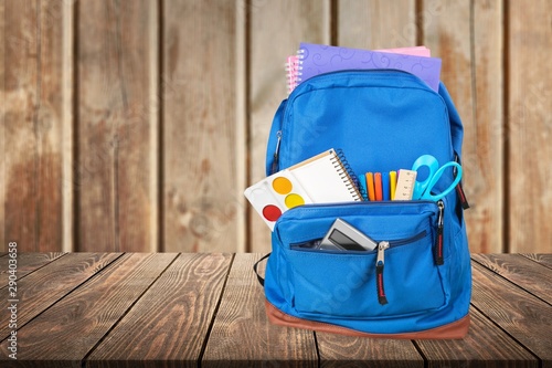 School Backpack with supplies on wooden background