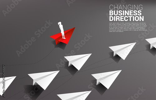 Silhouette of businesswoman standing on red origami paper airplane is move apart direction from group of white. Business Concept of disruption and niche marketing