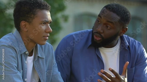 Afro-american father and teenager arguing, boy feeling unhappy, rebellious age