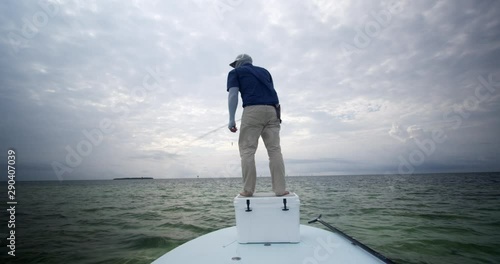Caucasian fisherman fly fishing on skiff boat