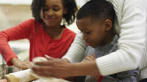 Black family sprinkling flour on rolling pin and dough