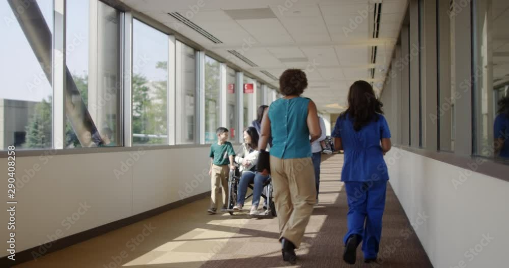Nurse pushing mother of newborn baby in corridor with family Nurse pushing mother of newborn baby in corridor with family