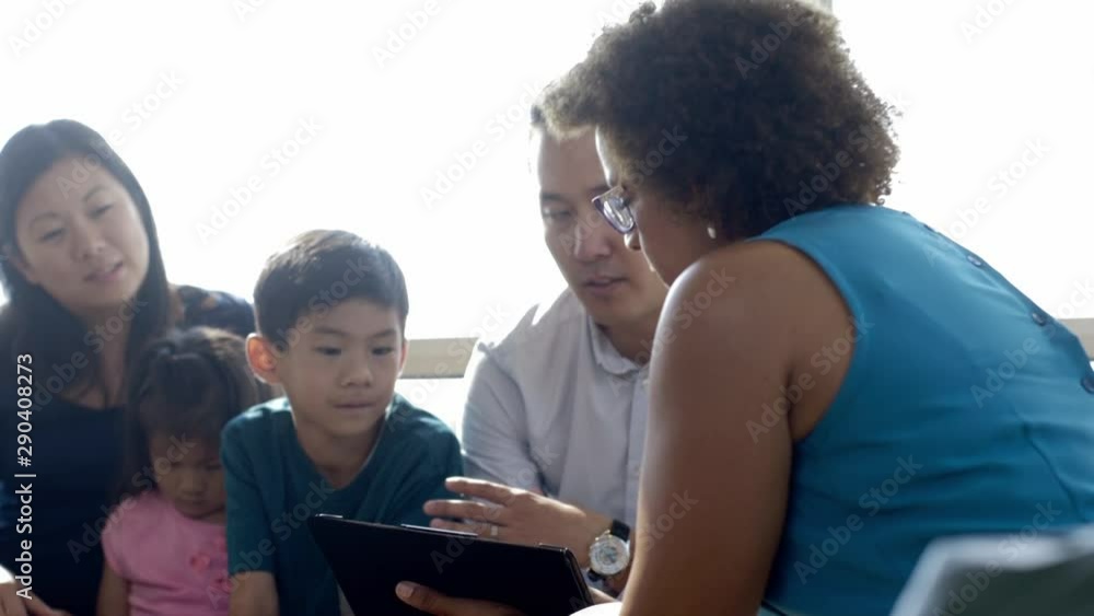 Doctor with digital tablet talking to family in hospital lobby Doctor with digital tablet talking to family in hospital lobby
