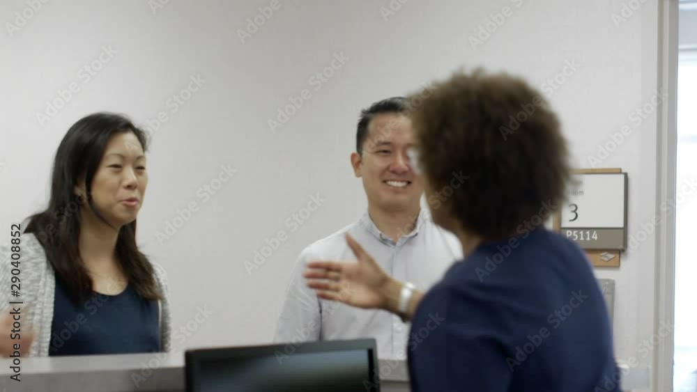 Nurse greeting couple at desk in hospital Nurse greeting couple at desk in hospital