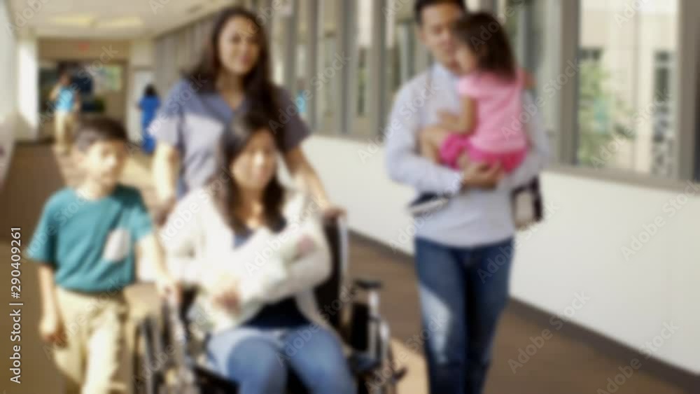 Nurse pushing mother of newborn baby in corridor with family Nurse pushing mother of newborn baby in corridor with family