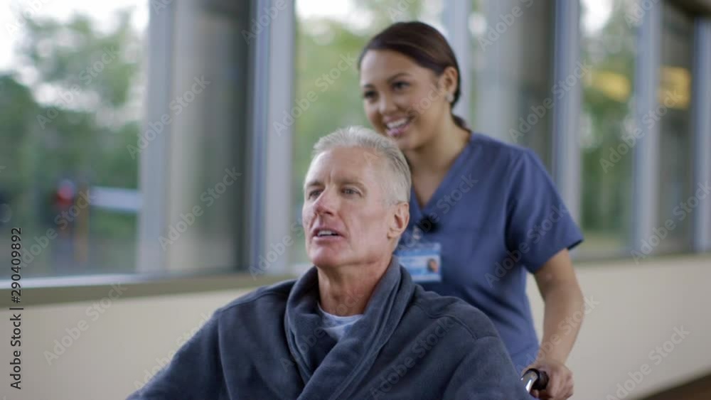 Nurse pushing patient in wheelchair in hospital corridor Nurse pushing patient in wheelchair in hospital corridor