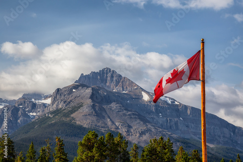 Canadian Flag with Rockie Mountains in the background during a sunny summer day. Taken in Banff National Park, Alberta, Canada.