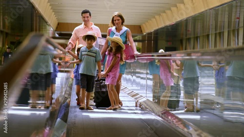 Smiling family walking on travolator at airport