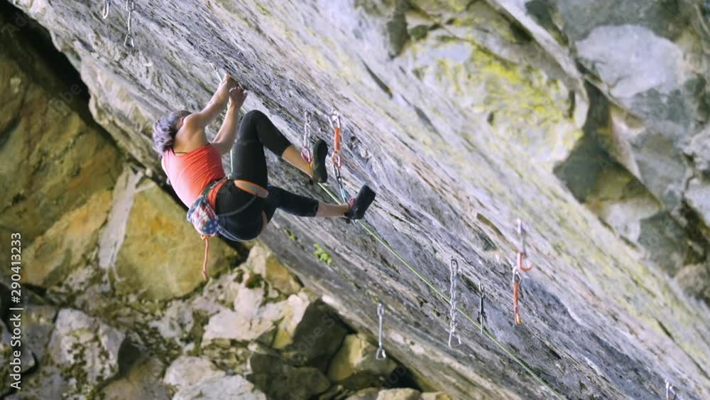 Wide panning shot of girl climbing rock and falling
