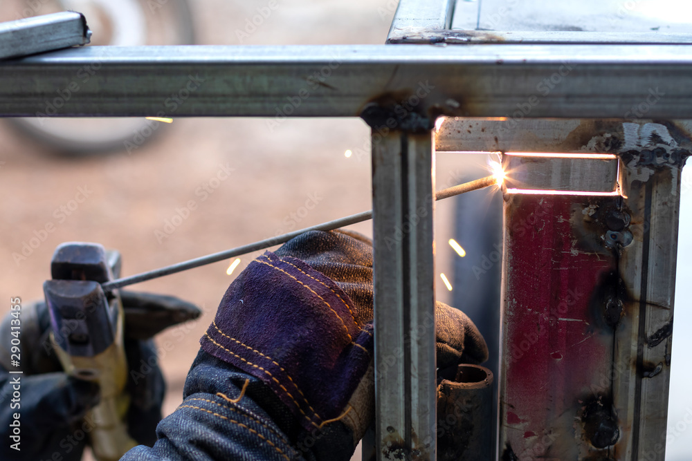 Close-up of a worker wearing gloves, welding metal.