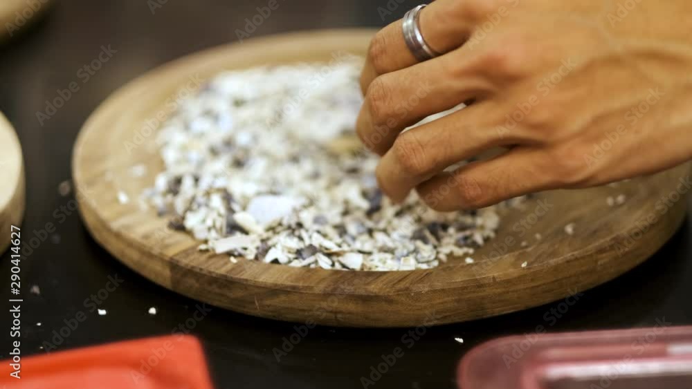 Close-up handheld shot of hands laying down crushed seashells on a wooden plate as part of decorations Close-up handheld shot of hands laying down crushed seashells on a wooden plate as part of decorations
