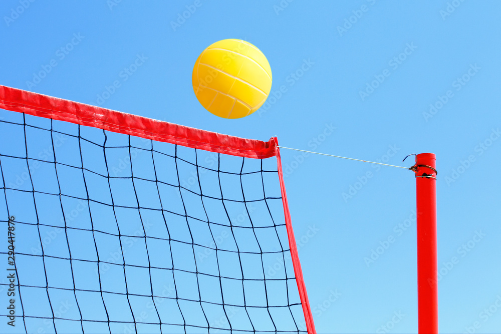 volleyball on the beach, net and yellow ball on blue sky