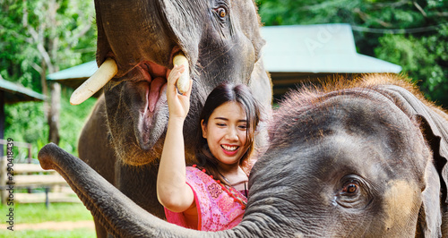 female thai tourist having fun with baby and mother elephant at sanctuary in thailand photo