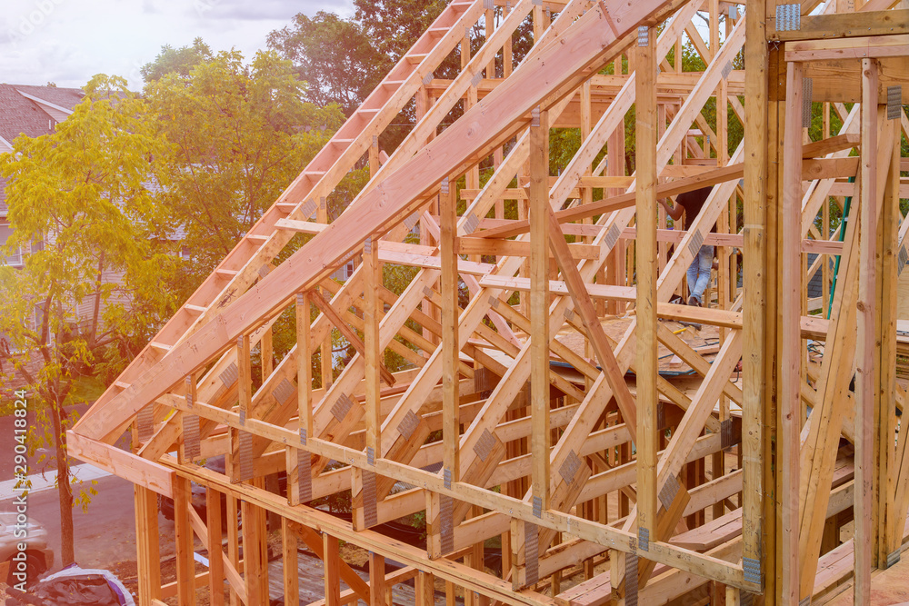 Panorama of condominium building with under construction wooden house with timber framing, truss, joist, beam close-up
