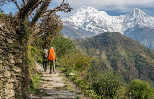 Couple of tourist walking and visiting the Annapurna Sanctuary trek with beautiful view of Mt.Annapurna and Mt.Hiunchuli in the background.