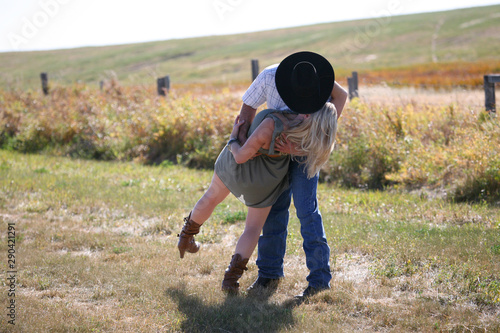Young cowboy and cowgirl kissing in a field 