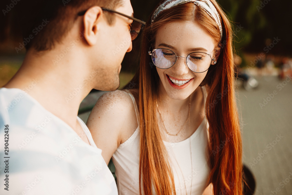 Close up of a young red haired woman with freckles laughing with closed eyes dating with her man. Beautiful couple dating outdoor and having fun. Close up of a young red haired woman with freckles laughing with closed eyes dating with her man. Beautiful couple dating outdoor and having fun.