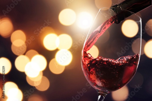 Red wine pouring in glass on  background