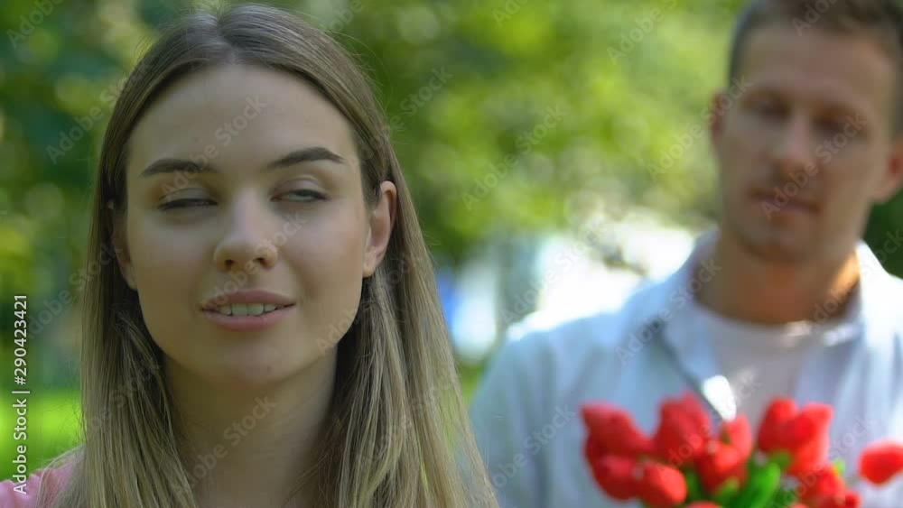 Self-confident woman ignoring man with bouquet of tulips, unrequited love Self-confident woman ignoring man with bouquet of tulips, unrequited love