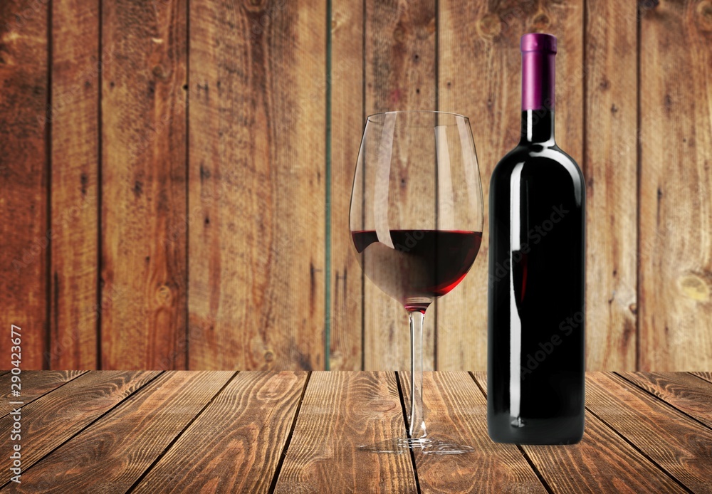 Red wine glass on wooden desk at wall background