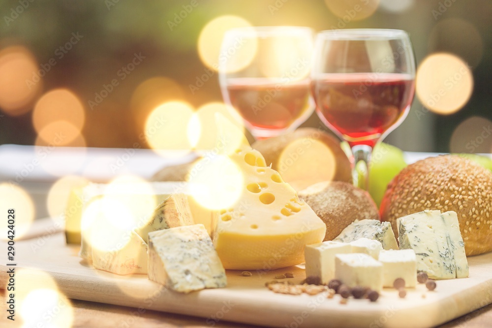 Assortment of cheese on board and two glasses of wine
