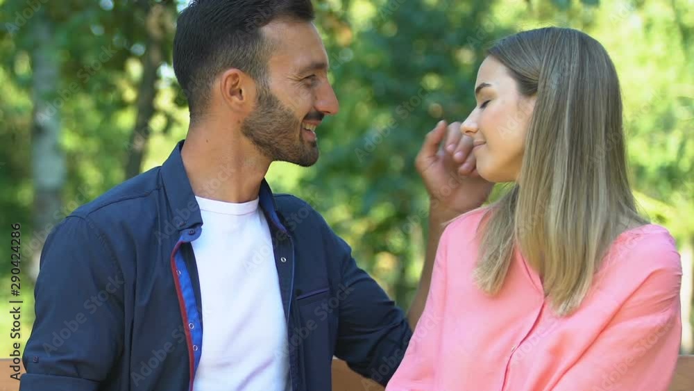 Man and woman in love admiring each other sitting on bench in park, romance Man and woman in love admiring each other sitting on bench in park, romance