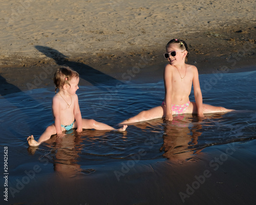 Children play in the water, beach vacation. Evening light.