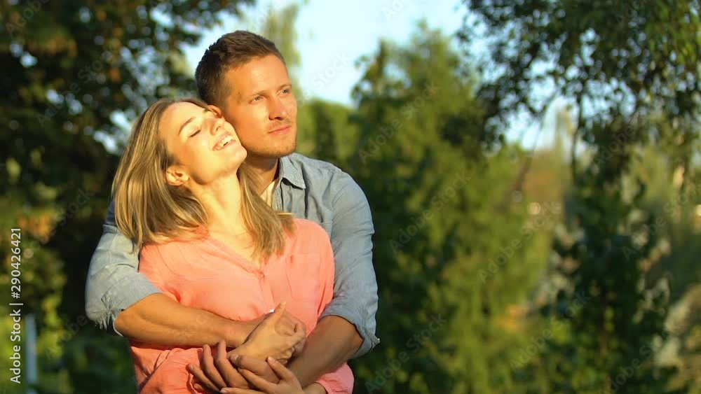 Man and woman in love admiring beautiful sunset tenderly embracing, magic hour Man and woman in love admiring beautiful sunset tenderly embracing, magic hour