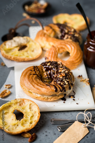 Eclairs (choux pastry) with custard, chocolate and nuts. Custard rings.