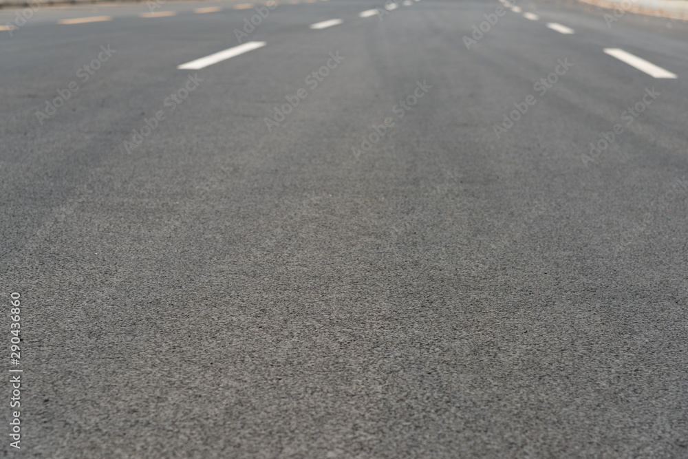 Wide asphalt road pavement and white paint line low angle view background