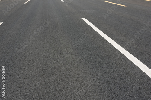 Wide asphalt road pavement and white paint line low angle view background © bqmeng