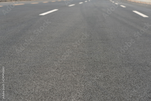 Wide asphalt road pavement and white paint line low angle view background © bqmeng