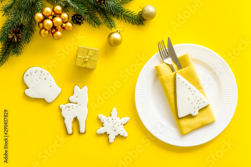 Fototapeta Naklejka Na Ścianę i Meble -  Table setting for new year 2020 celebration with pine, decorations, plate and tableware yellow background top view