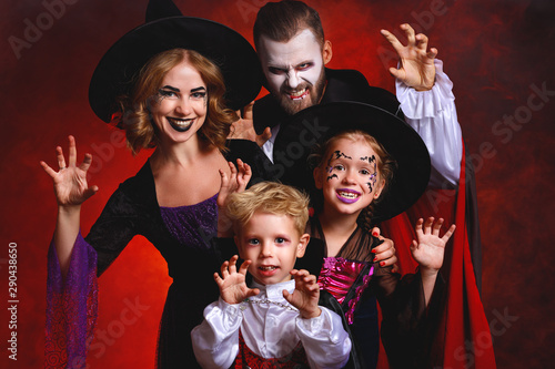 happy family mother father and children in costumes and makeup on Halloween on dark red background.